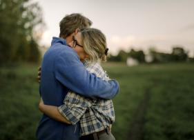 a woman hugging a man for support in a field