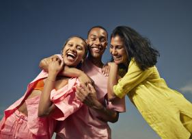 a group of 3 friends with their arms around each other against a blue background