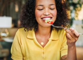 a woman in yellow eating something with a fork