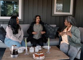 a group of women sitting on a couch around a table in deep discussion