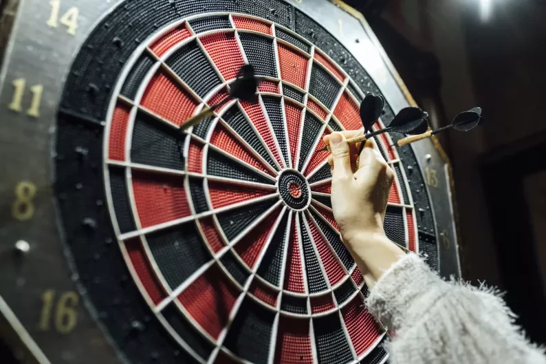 a hand picking darts off a dartboard