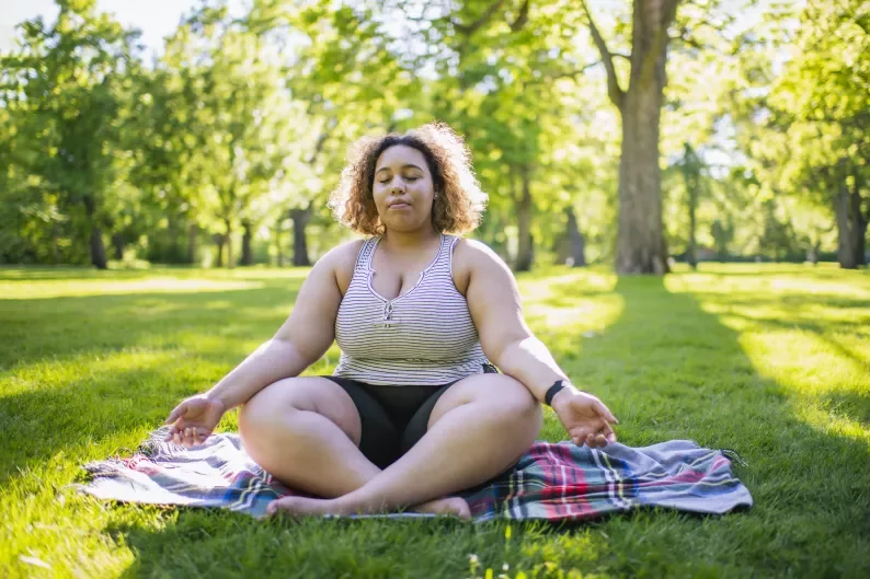 woman sitting on a picnic mat in a lotus pose.
