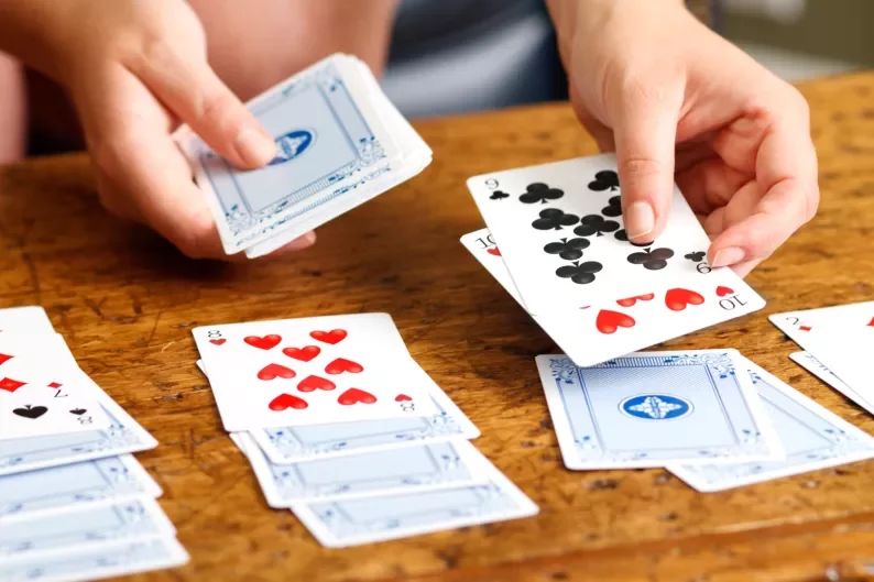 two hands dealing out cards to play solitaire