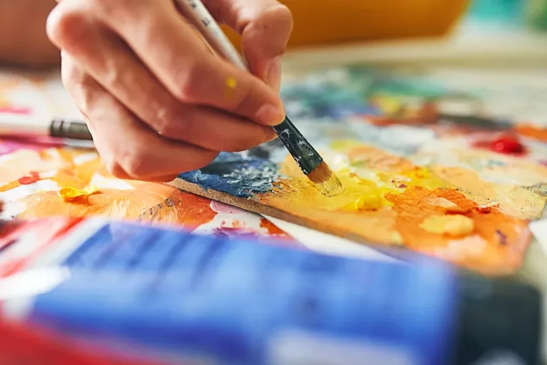 a hand holding a paint brush next to a palette