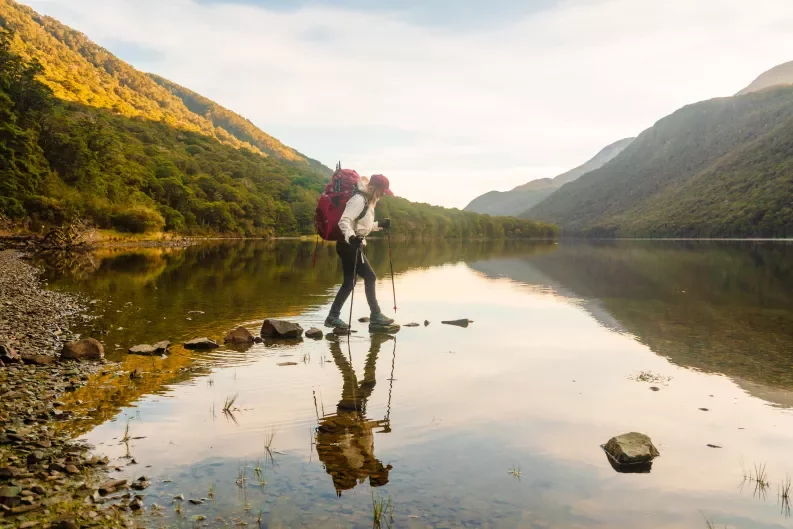 a woman hiking across a pond