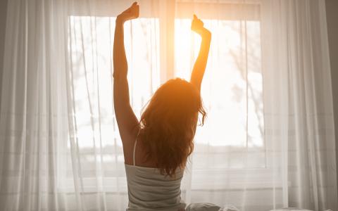 a woman stretching in bed in front of a window