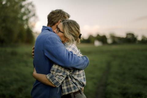 a woman hugging a man for support in a field