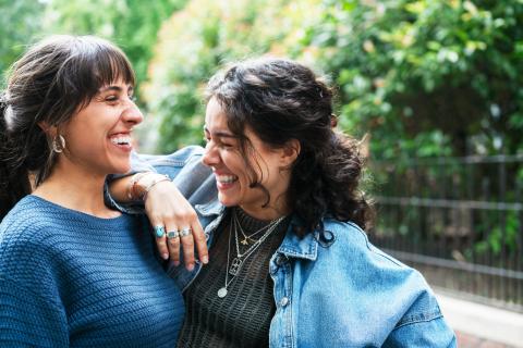 two women laughing, one of them has her elbow on the other's shoulder