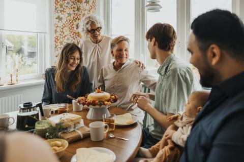 a family surrounding a cake at a dinner table